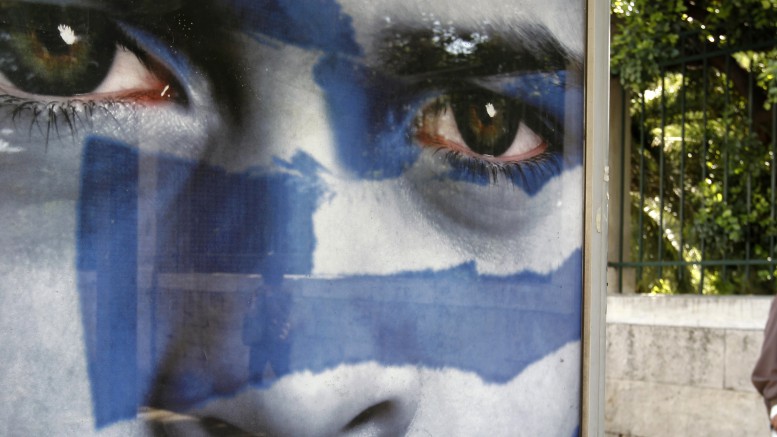 A man walks past a pre-election poster of the Democratic Alliance party at a bus station in Athens